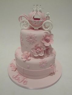 a three tiered cake with pink flowers and a crown on top