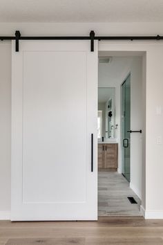 an open sliding door in the middle of a room with hardwood floors and white walls