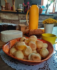 a bowl filled with doughnuts sitting on top of a table next to a yellow cup