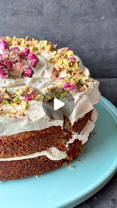 a cake with white frosting and pink flowers on it sitting on a blue plate