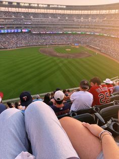 a person sitting in the stands at a baseball game with their feet on his knees