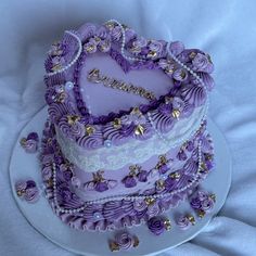 a heart shaped cake with purple icing and gold decorations on it's sides