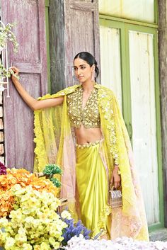 Shine bright like a diamond at this seasons soirees. The lime green set comes with a blouse covered with daisy flower applique work. The dhoti-style skirt also glamourizes the outfit with its asymmetrical look. The dupatta/cape that is paired with the outfit has an ombre effect to tie in all the colors of the embellishments. Pista Green Sharara For Party, Spring Saree Set With Mirror Work, Pista Green Embellished Pre-draped Saree For Diwali, Pista Green Embellished Saree For Diwali, Embellished Pista Green Pre-draped Saree For Diwali, Diwali Embellished Pista Green Pre-draped Saree, Festive Pista Green Pre-draped Saree For Party, Yellow Lehenga For Spring, Spring Yellow Lehenga