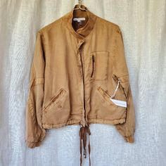 Young Fabulous And Broke Clara Bomber Jacket In A Beautiful Camel Color, Like A Rusty Tan, And Perfect For Fall. Medium Weight, Comfortable Tencel Fabric, Fully Lined. Elasticized Cuffs, Drawstrings Front And Back At Hemline. Contemporary Styling Details Include Contrast Fabric X On Each Sleeve And A Vee Cut Out At Back Hem Plus Interesting Stitching Up The Center. Mandarin Collar. Full Zip Metal Zipper. Left Breast Functional Pocket With Its Own Metal Zipper. Two Functional Slant Pockets Where Brown Long Sleeve Utility Jacket, Spring Camel Outerwear With Pockets, Brown Utility Jacket With Pockets For Spring, Spring Brown Utility Jacket With Pockets, Spring Brown Utility Jacket, Neutral Long Sleeve Utility Outerwear, Neutral Utility Outerwear With Long Sleeves, Vintage Brown Utility Jacket For Spring, Tencel Fabric