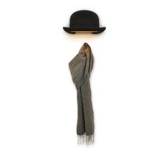 a black hat and scarf hanging on a white wall with a light coming from it