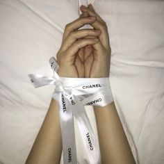 a person laying in bed with their hands wrapped around the wristbands that say chanel