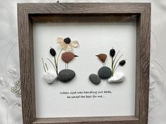 three pebbles and flowers in a wooden frame