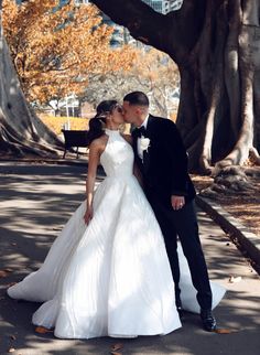 a bride and groom kissing on the street