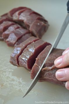 a person cutting meat with a knife on a counter