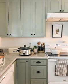 a kitchen with white cabinets and gray counter tops