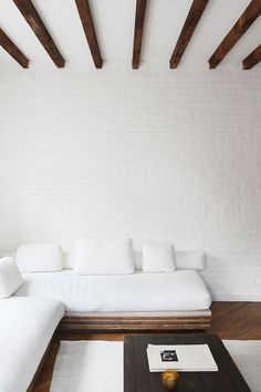 a living room with white couches and wooden beams