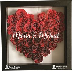 a heart made out of rolled up red roses in a black frame with the words maura & michael written on it