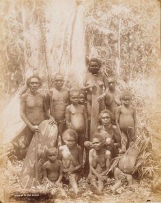 a group of men standing next to each other in front of some trees and bushes