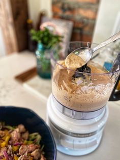 a blender filled with food on top of a counter next to a bowl of salad