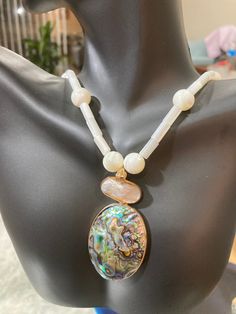 This fashionable abalone (mother of pearl) necklace and reversible pendant is striking with its contrasting tones.  The soft, white abalone necklace looks beautiful against the dark large pendant.  The pendant consists of two adjoining pieces, each framed in gold tone metal.  The larger abalone piece is a rich green with magenta and blue overtones.  The other side of this piece is white, making the necklace able to be worn as a reversible, all-white necklace and pendant.  The smaller adjoining p White Oval Mother Of Pearl Necklace, White Mother Of Pearl Oval Necklace, Oval White Mother Of Pearl Necklace, Elegant White Abalone Shell Jewelry, Oval Mother Of Pearl Necklace, Abalone Necklace, Mother Of Pearl Necklace, Stylish Necklace, Rich Green