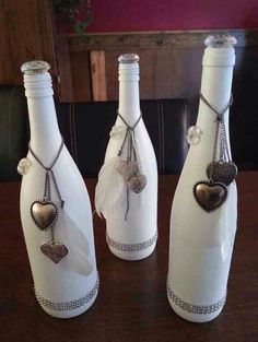 three white wine bottles decorated with hearts and pearls