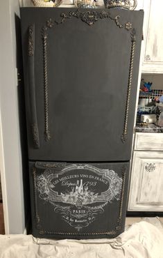 an old fashioned refrigerator is painted black and has ornate designs on the front, with white trim