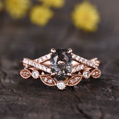 a fancy ring with a black diamond surrounded by white and brown diamonds on a piece of wood