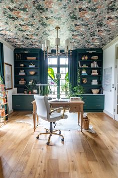 a home office with floral wallpaper on the ceiling and wooden flooring, along with a white chair