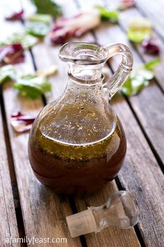 a brown glass bottle sitting on top of a wooden table next to leaves and flowers