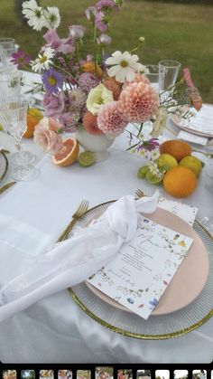 the table is set with flowers, oranges and other items for an elegant dinner