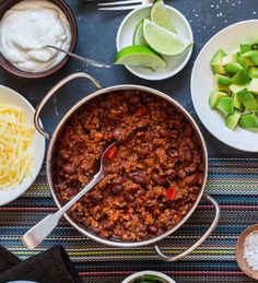 an overhead view of chili, cheese and avocado on a table with other ingredients