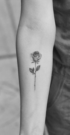 a black and white photo of a rose tattoo on the left inner arm with leaves