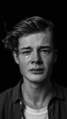 black and white photograph of a young man with tears on his face, looking at the camera