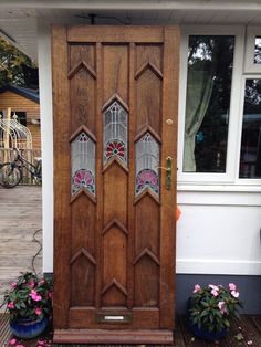 two potted plants are next to a wooden door with stained glass panels on it