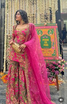 a woman in a pink and gold outfit standing next to a sign that says paper pind