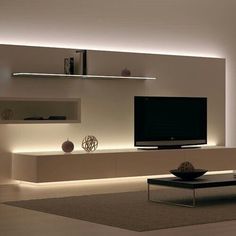 a modern living room with white walls and shelves on the wall, along with a large flat screen tv