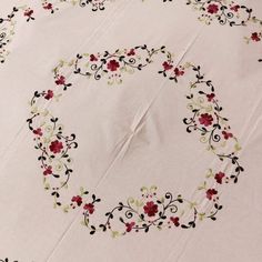 an embroidered tablecloth with red flowers on it