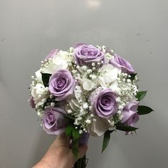 a hand holding a bouquet of purple and white flowers