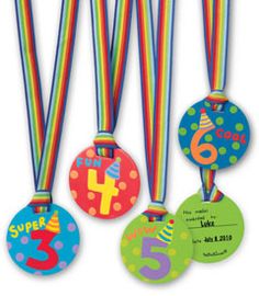 three birthday medals with colorful ribbons and numbers on them, one for each child's age