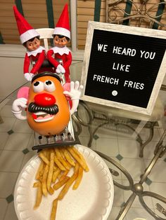 two elfs sitting on top of a plate with french fries in front of them