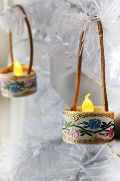 two small candles are hanging from twine baskets