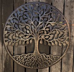 a metal tree wall hanging on a wooden fence