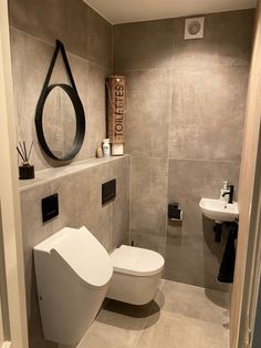 a bathroom with a toilet, sink and mirror on the wall next to each other