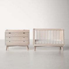 a baby crib next to a dresser with drawers on each side and a chest of drawers in the middle