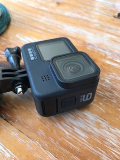 an action camera sitting on top of a wooden table next to a pair of scissors