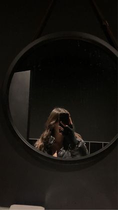 a woman taking a selfie in front of a mirror with her cell phone to her ear