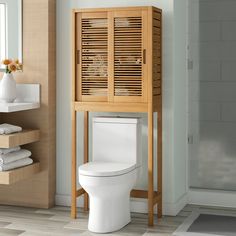 a wooden cabinet next to a toilet in a bathroom