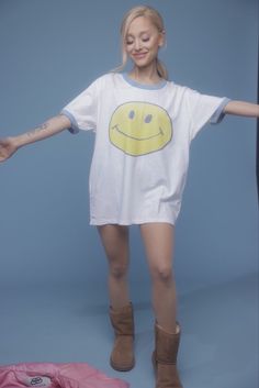 a woman with her arms out in front of the camera, wearing a smiley face t - shirt