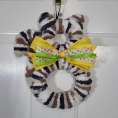 a zebra print wreath hanging on a door with polka dots and a yellow ribbon tied to it