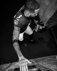 a man with tattoos on his arm and hand reaching for something in an open grate