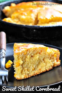 a slice of cornbread on a black plate with a fork and knife next to it