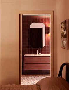 an open door leading to a bathroom with a sink and mirror on the wall next to a bed