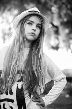 a young woman with long hair wearing a hat and t - shirt is posing for a black and white photo