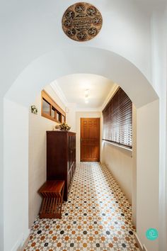 an archway leading to a hallway with a bench in the middle and a clock on the wall