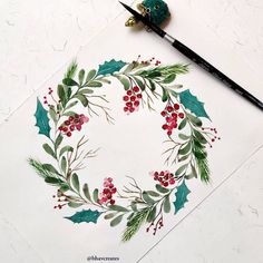 a wreath with holly and red berries painted on it next to a paintbrushes